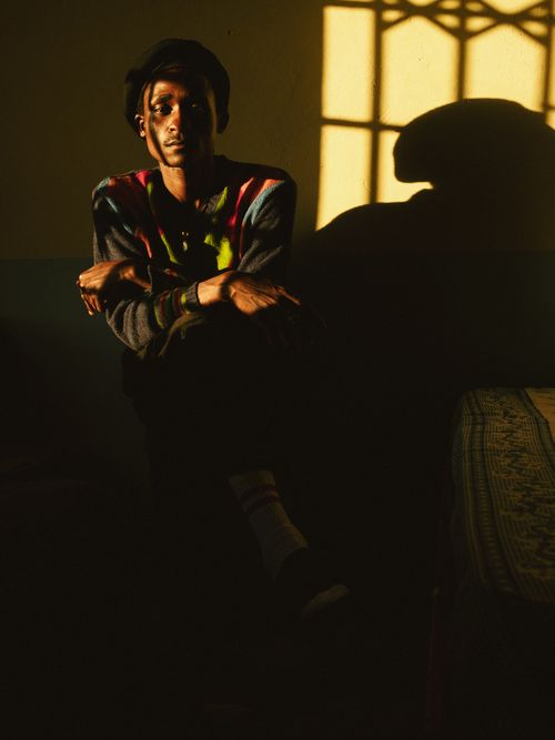 Free A contemplative man sitting indoors with dramatic sunlight and shadows. Stock Photo