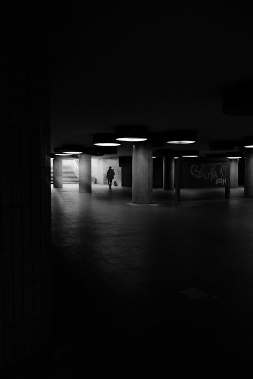 Free A black and white photo of a man walking in an empty subway Stock Photo