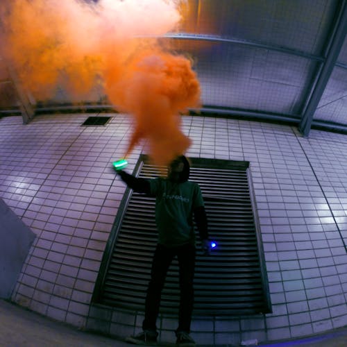 Free Man Holding Lighted Device over Orange Smoke Stock Photo