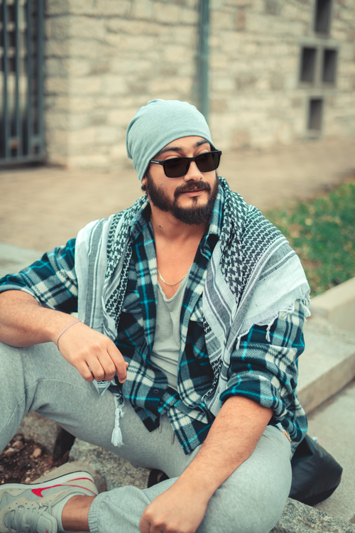 Free A bearded man wearing casual fashion outdoors, sitting with confidence and style. Stock Photo