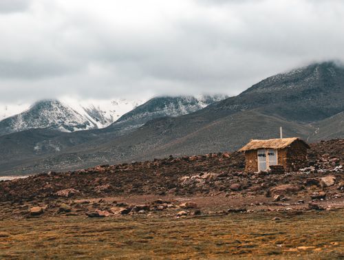 Free Rustic hut amid snow-capped mountains in Arequipa, Peru, showcasing serene rural winter landscape. Stock Photo