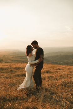 A couple enjoys a romantic embrace on a hillside during a Brazilian sunset.