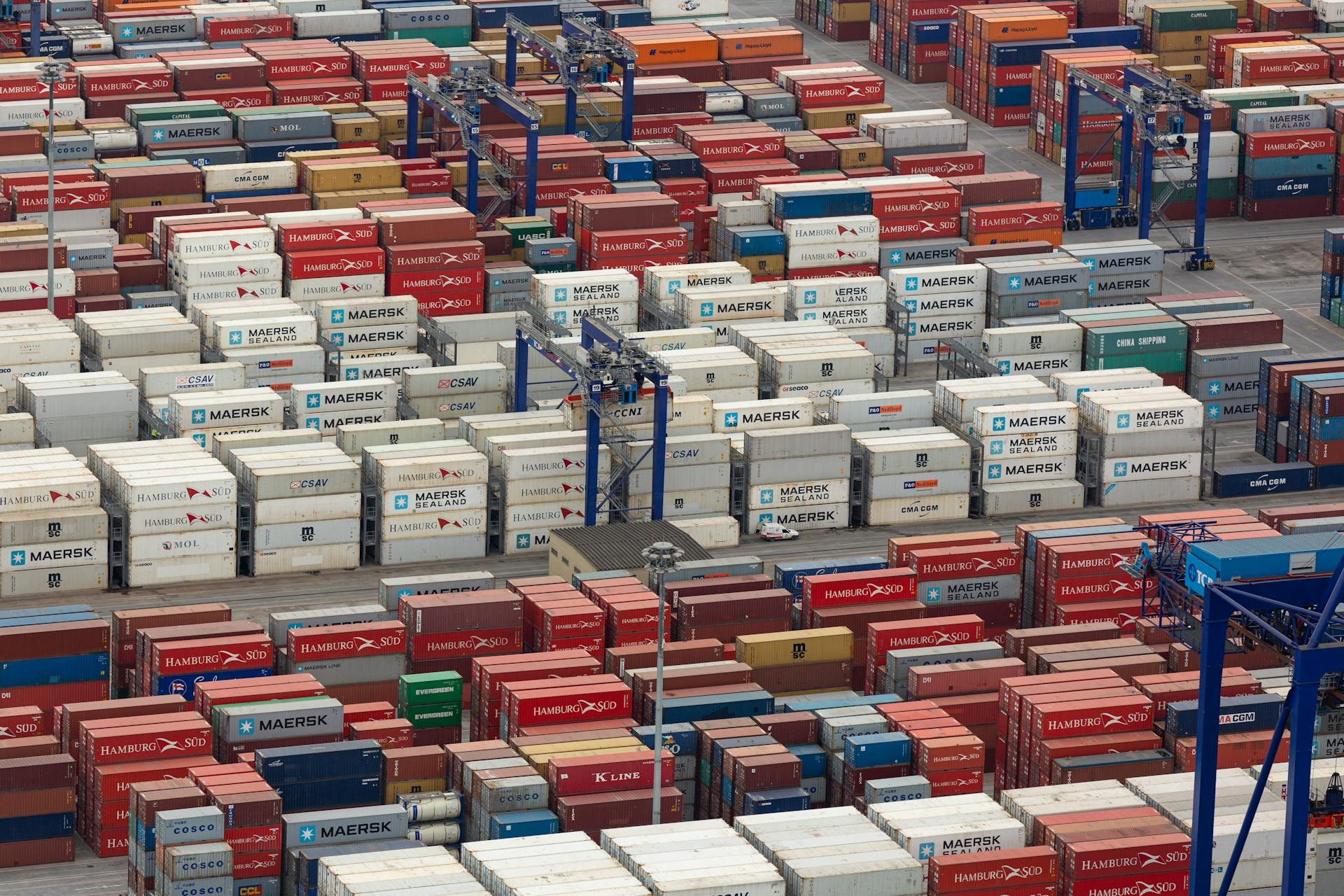 Aerial view of a bustling port with colorful cargo containers arranged in rows, showcasing logistics and trade.