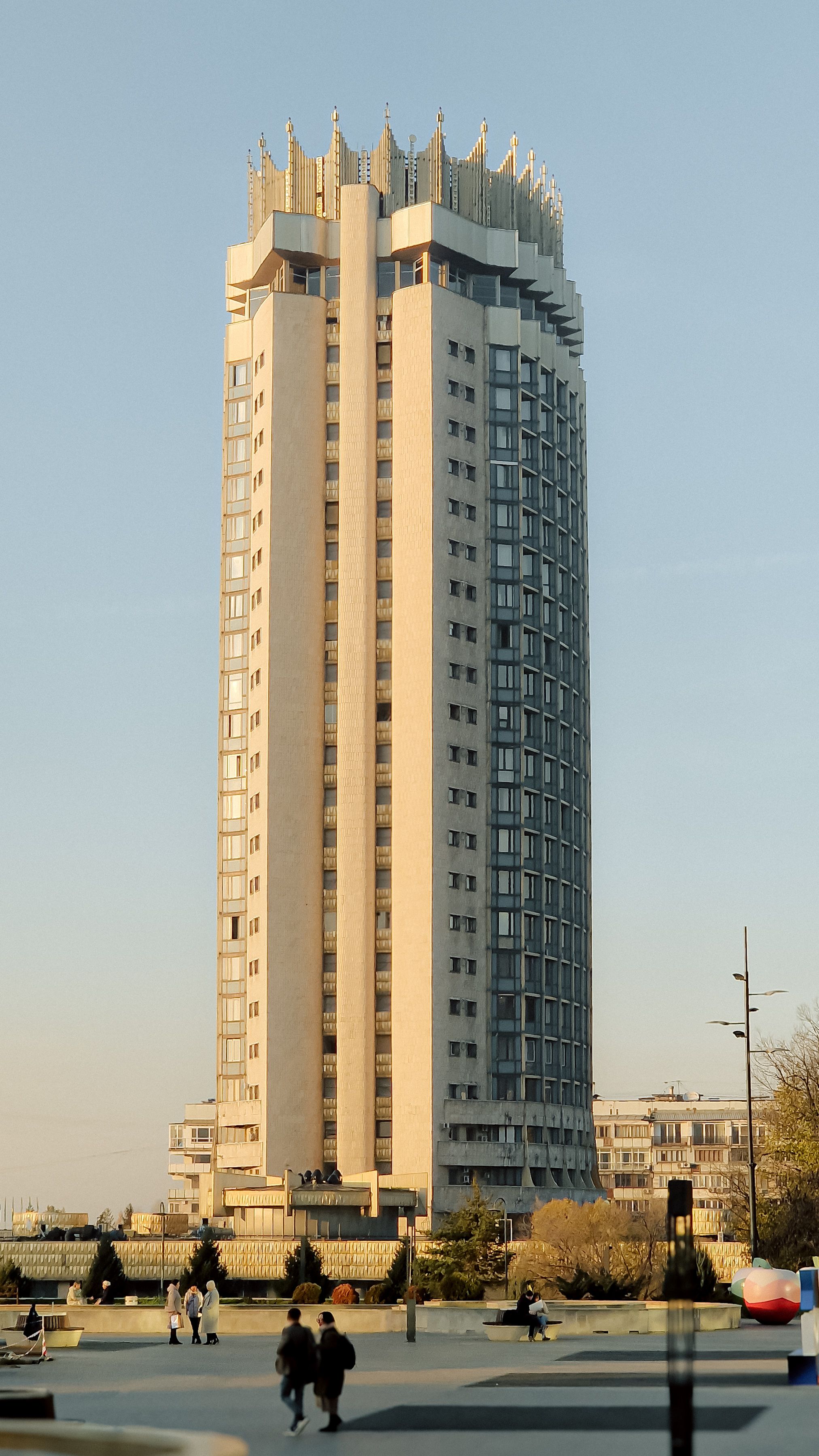 Vertical shot of a modern skyscraper in Almaty, Kazakhstan against a warm sunset sky.