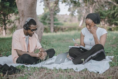 Free Two people enjoying a study session outdoors with a laptop and notebook, capturing leisure and focus. Stock Photo