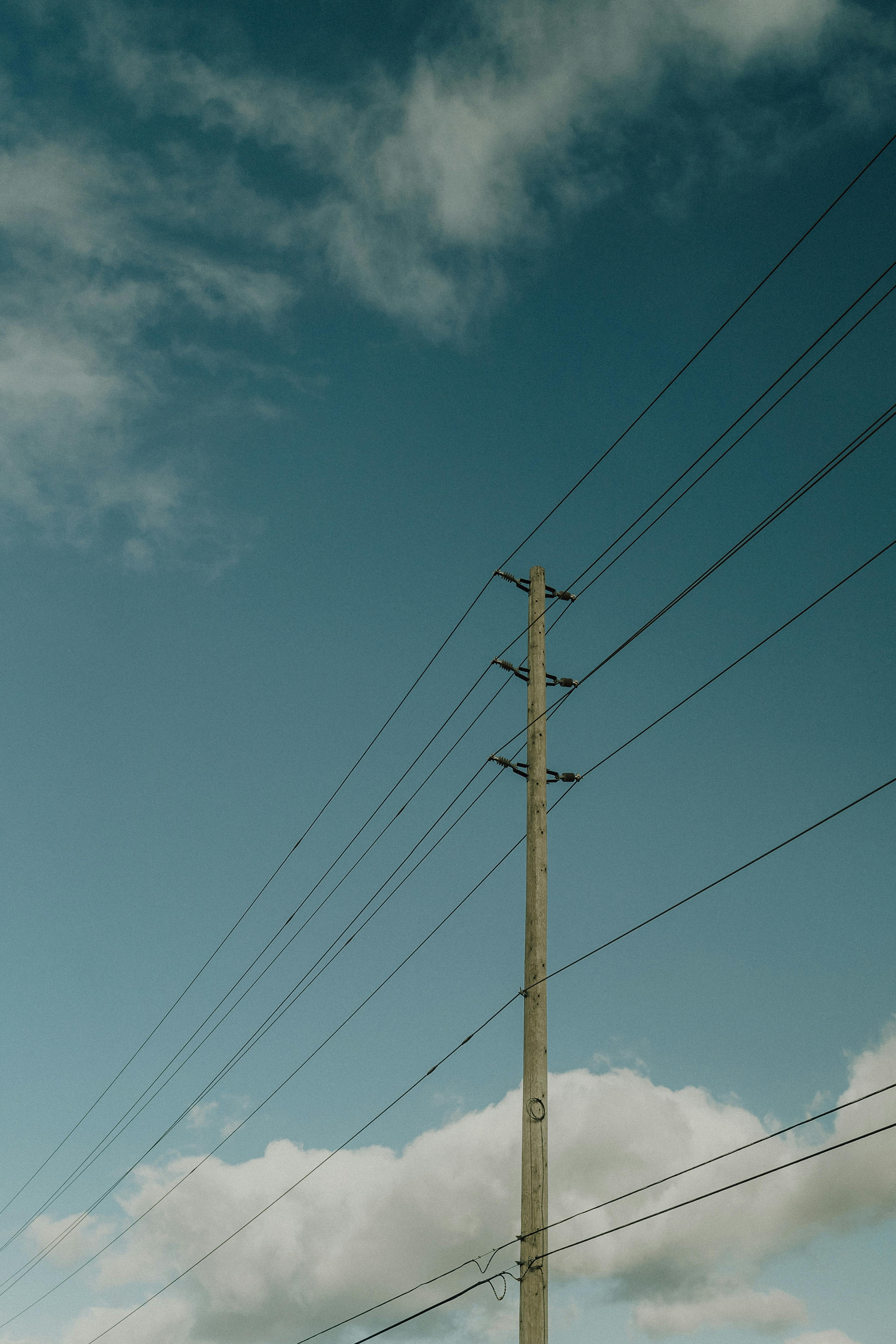 a power pole with a blue sky and clouds