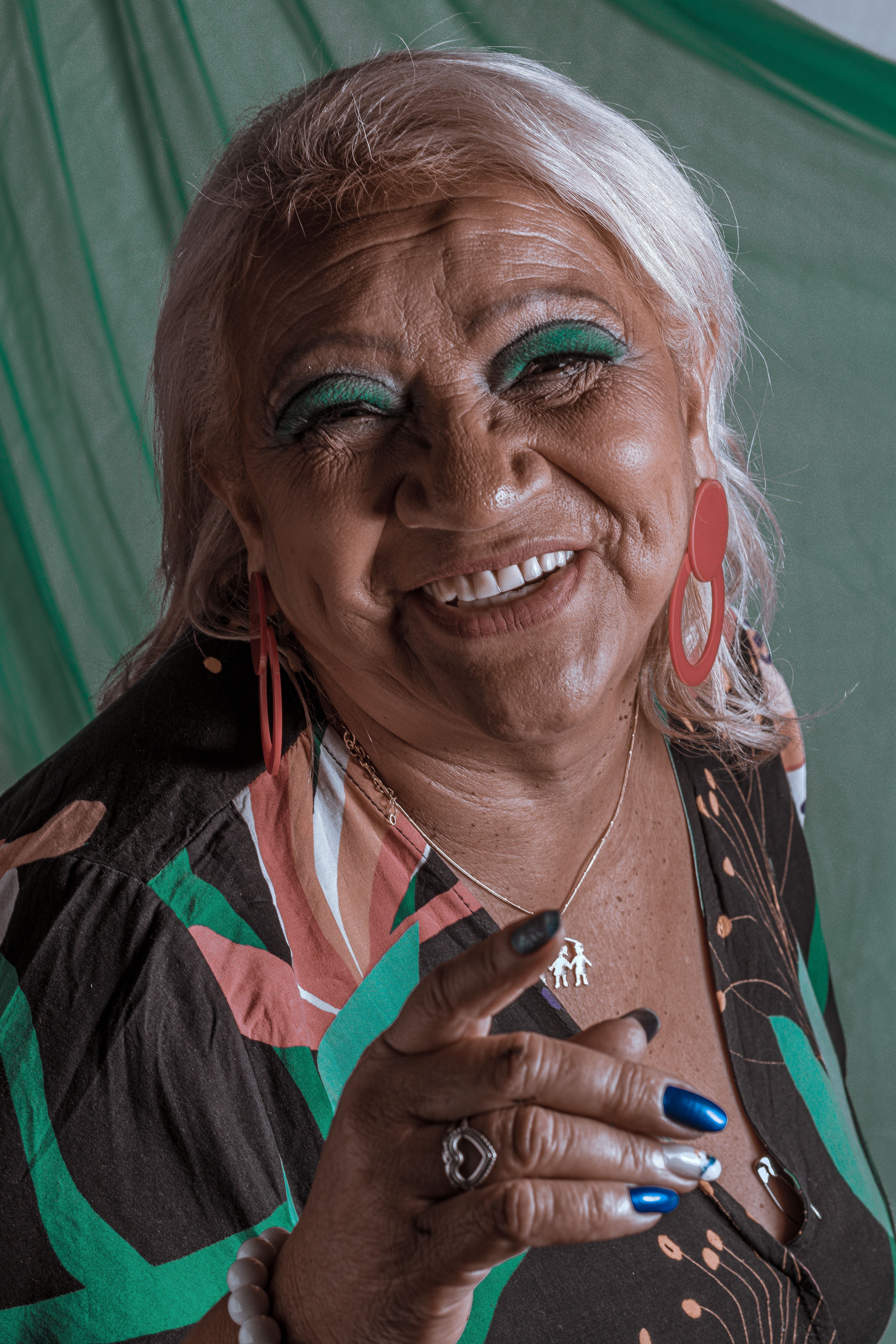 Smiling elderly woman with colorful makeup and accessories in a dynamic portrait shot.