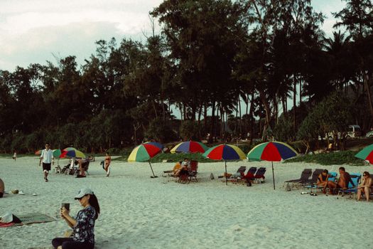 Relaxing beach scene with colorful umbrellas and people enjoying the summer sun.