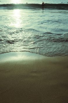 Peaceful view of sunlit waves on a sandy beach, evoking tranquility and natural beauty.