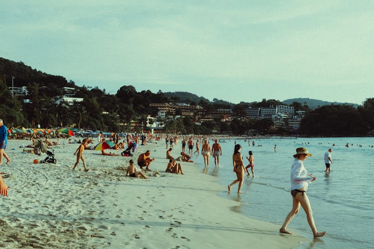 People Relaxing On Beach By Sea Shore