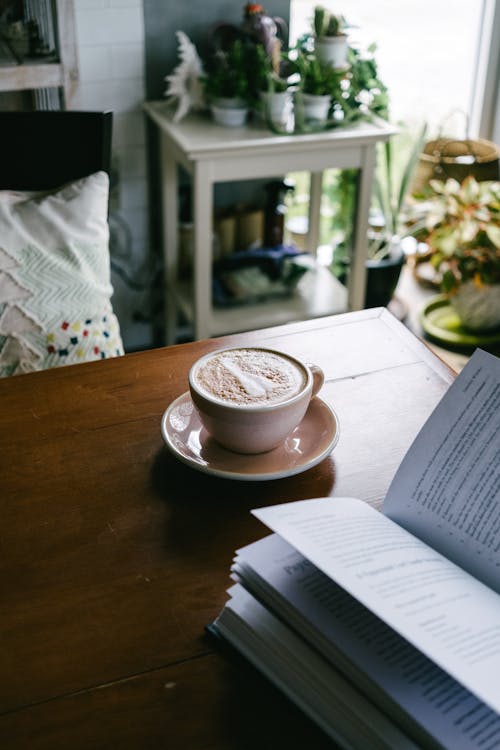 Cup of Coffee Set on Table next to Open Book