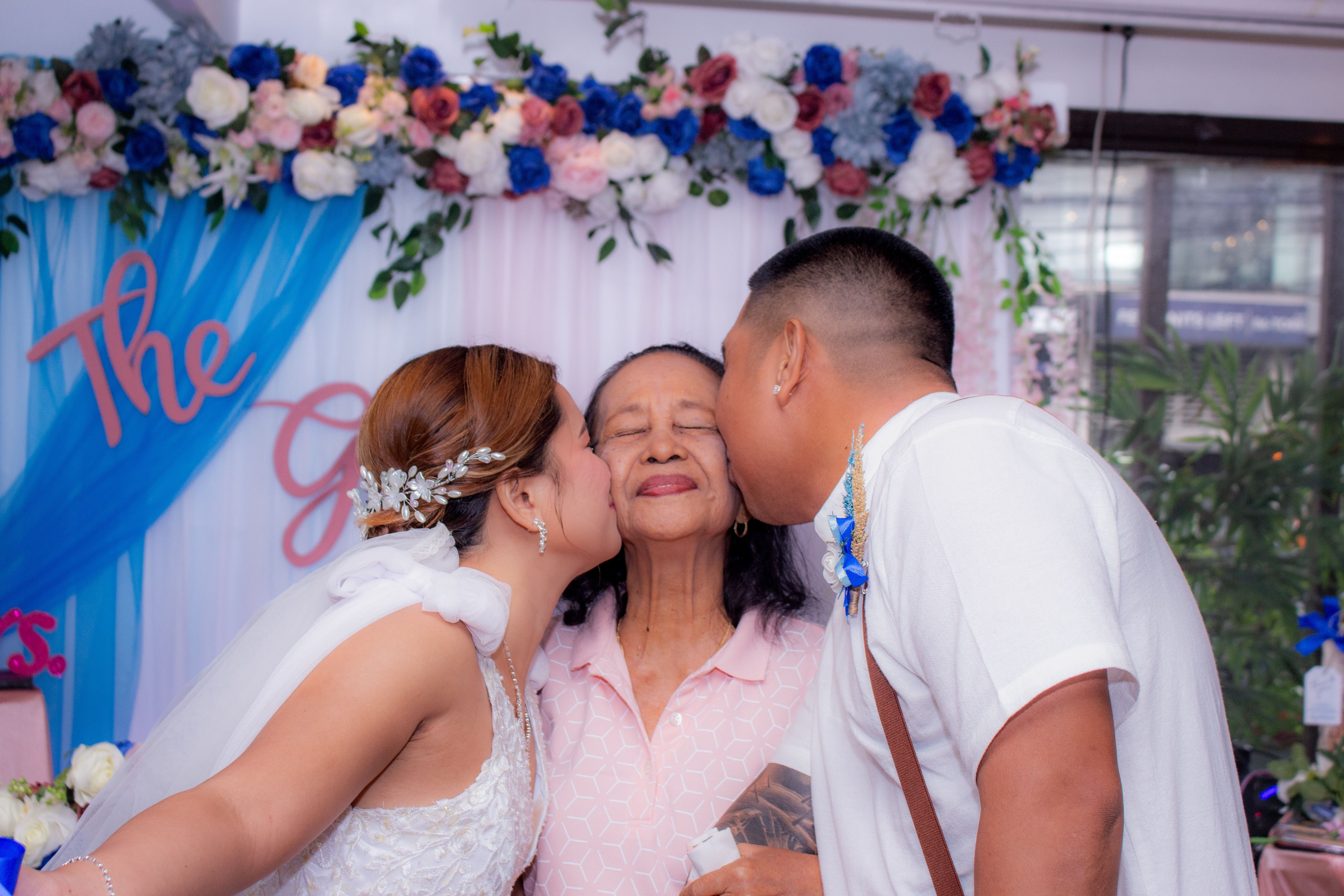A bride and groom sharing a loving moment with a grandmother during a wedding celebration.