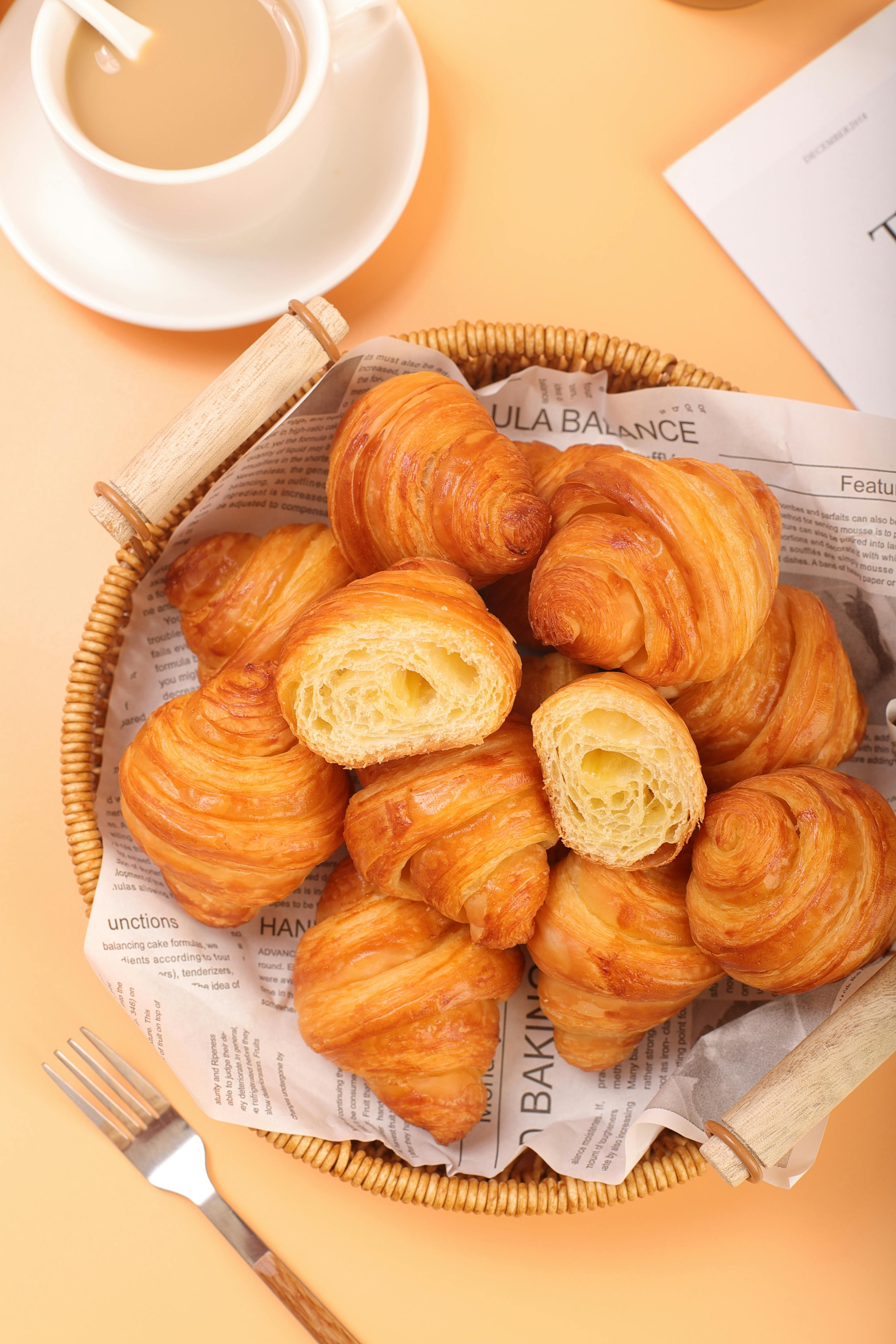 Freshly baked croissants arranged in a wicker basket, perfect for breakfast settings.