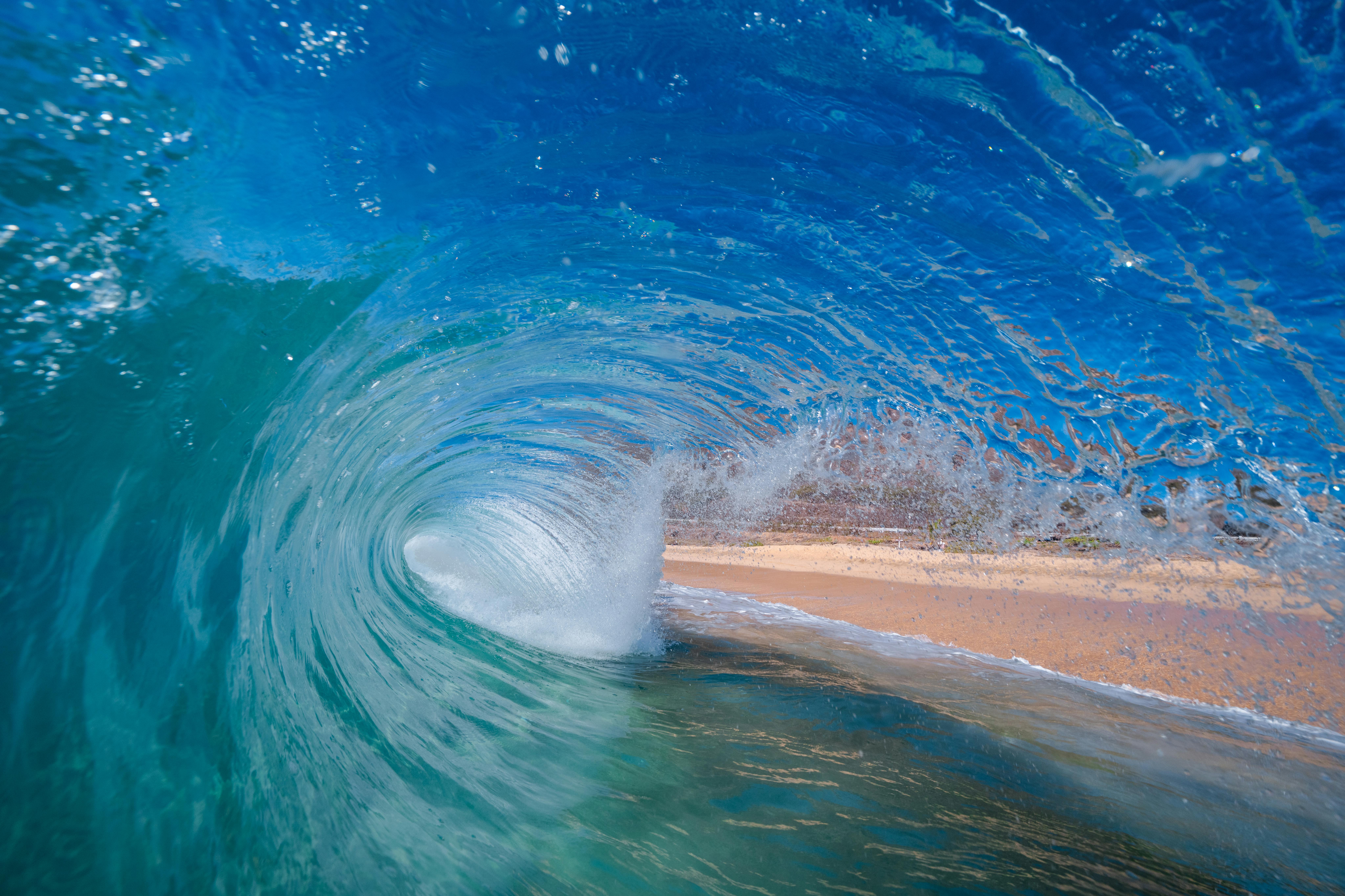 Experience the exhilarating view from inside a powerful barreling wave on a sunny beach day.