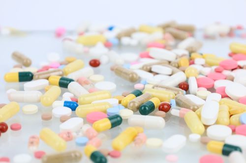 Free A vibrant assortment of pills and capsules scattered across a white surface representing medication and healthcare. Stock Photo