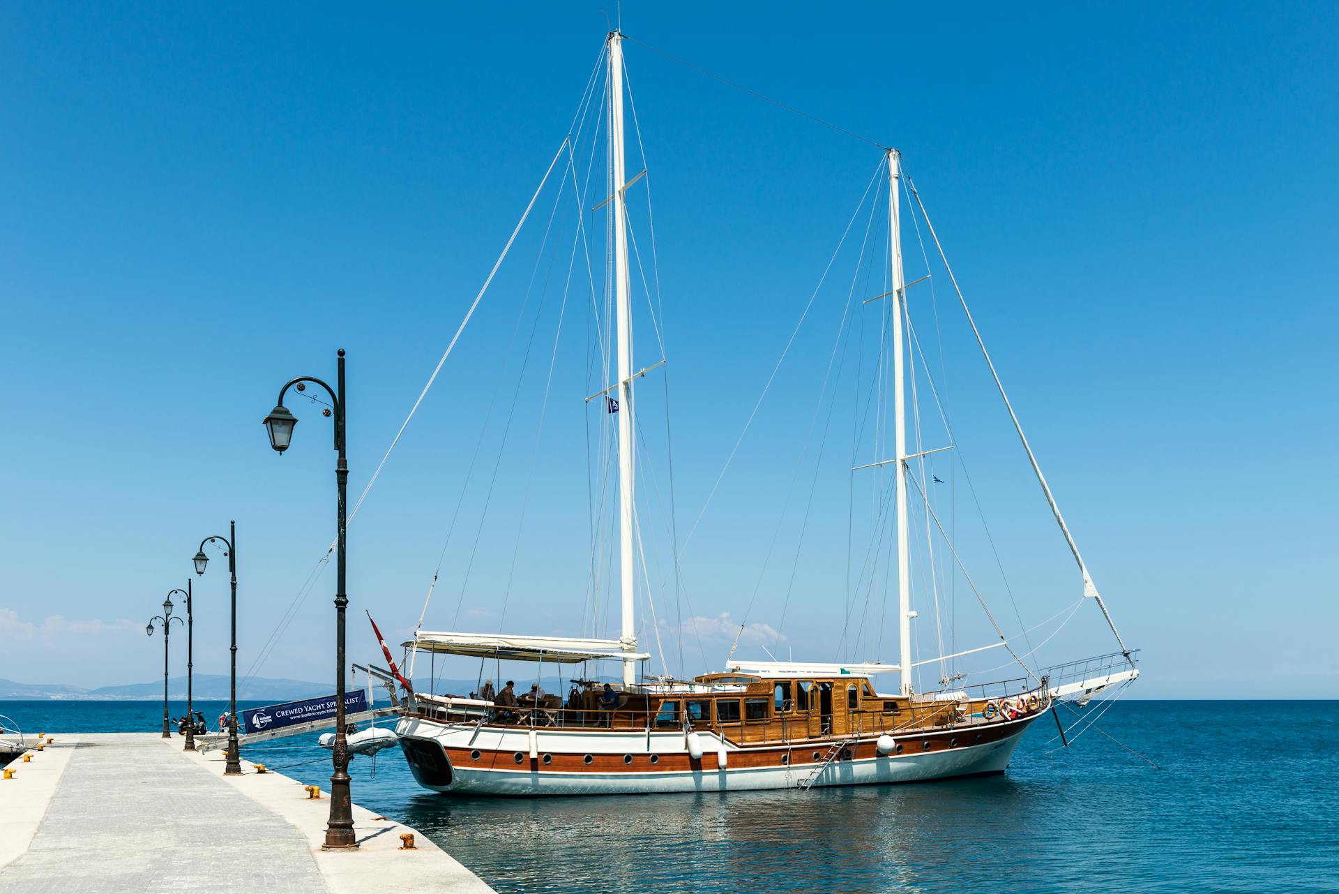 A stunning sailing yacht moored by the pier in Kos, Greece under a clear blue sky.
