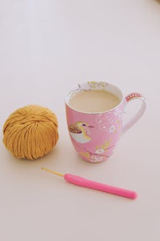 A vibrant scene with coffee, yarn, and crochet hook on a bright surface.