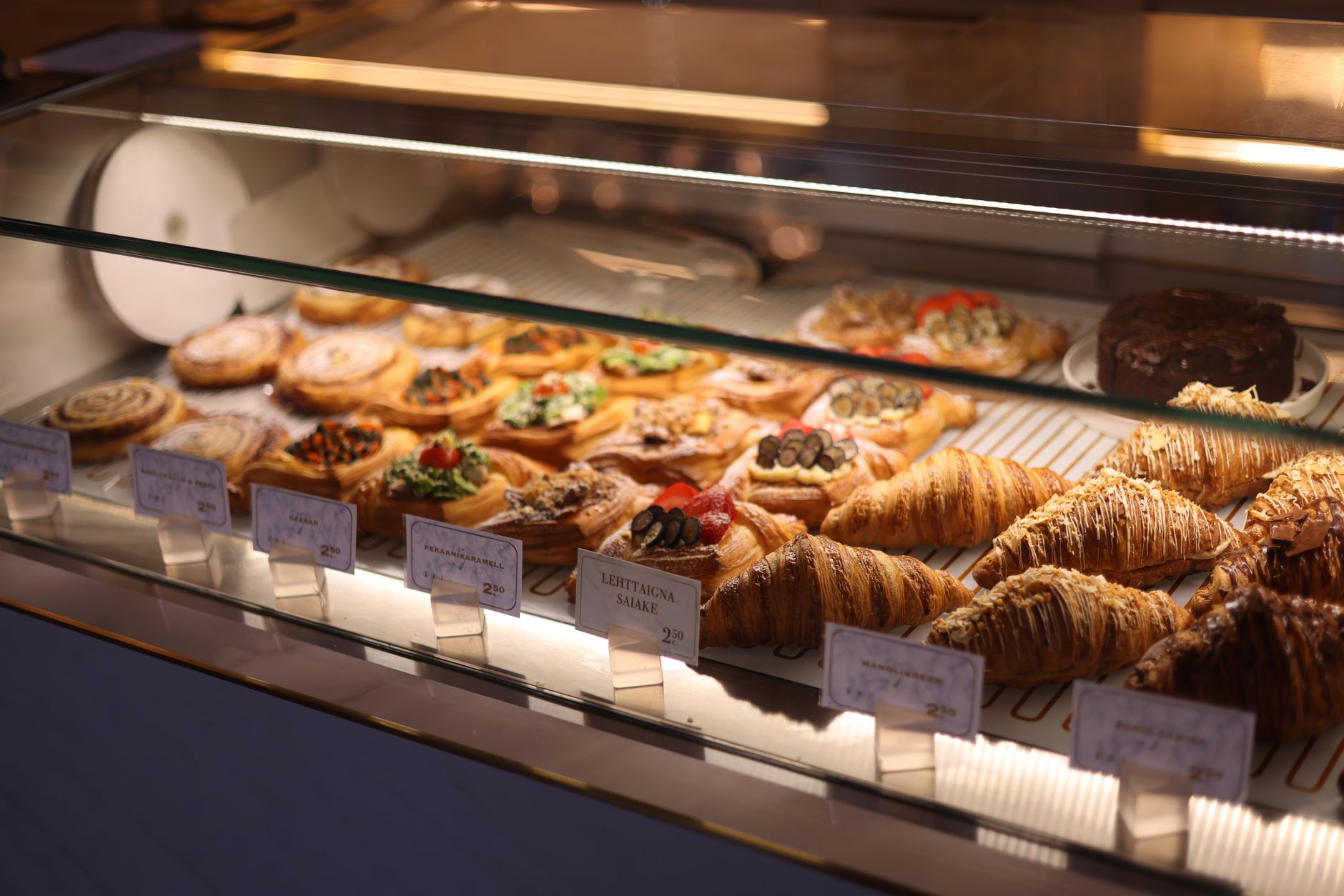 a bakery display case of pastries — croissants, danishes, and crumb cake