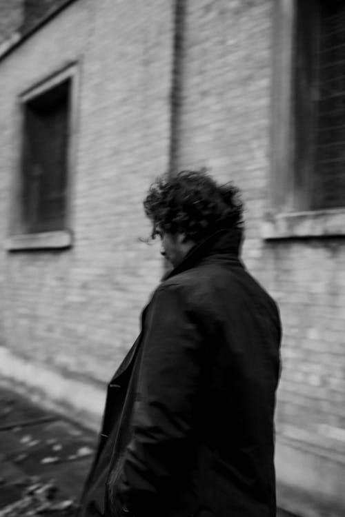 Passerby in a Trench Coat in Front of a Brick Building