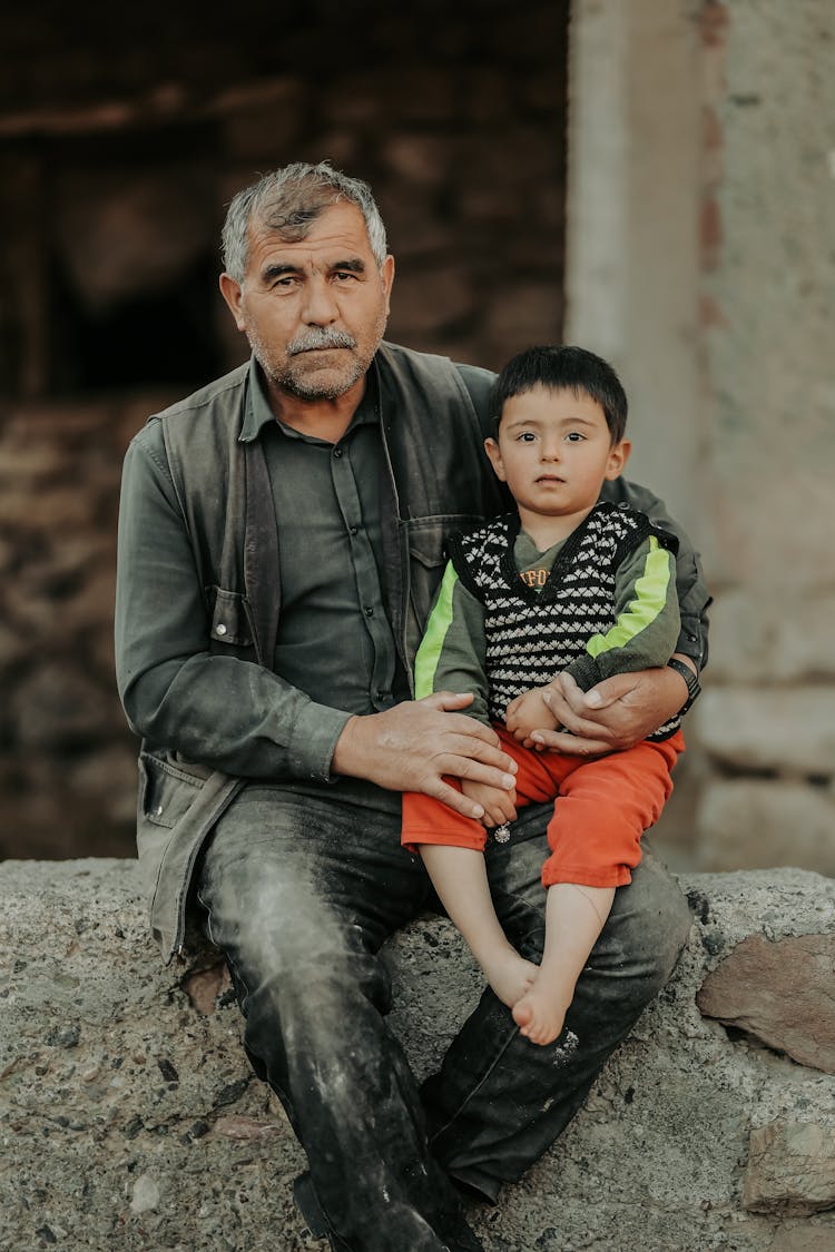 Elderly Man Sitting With Little Boy On Lap