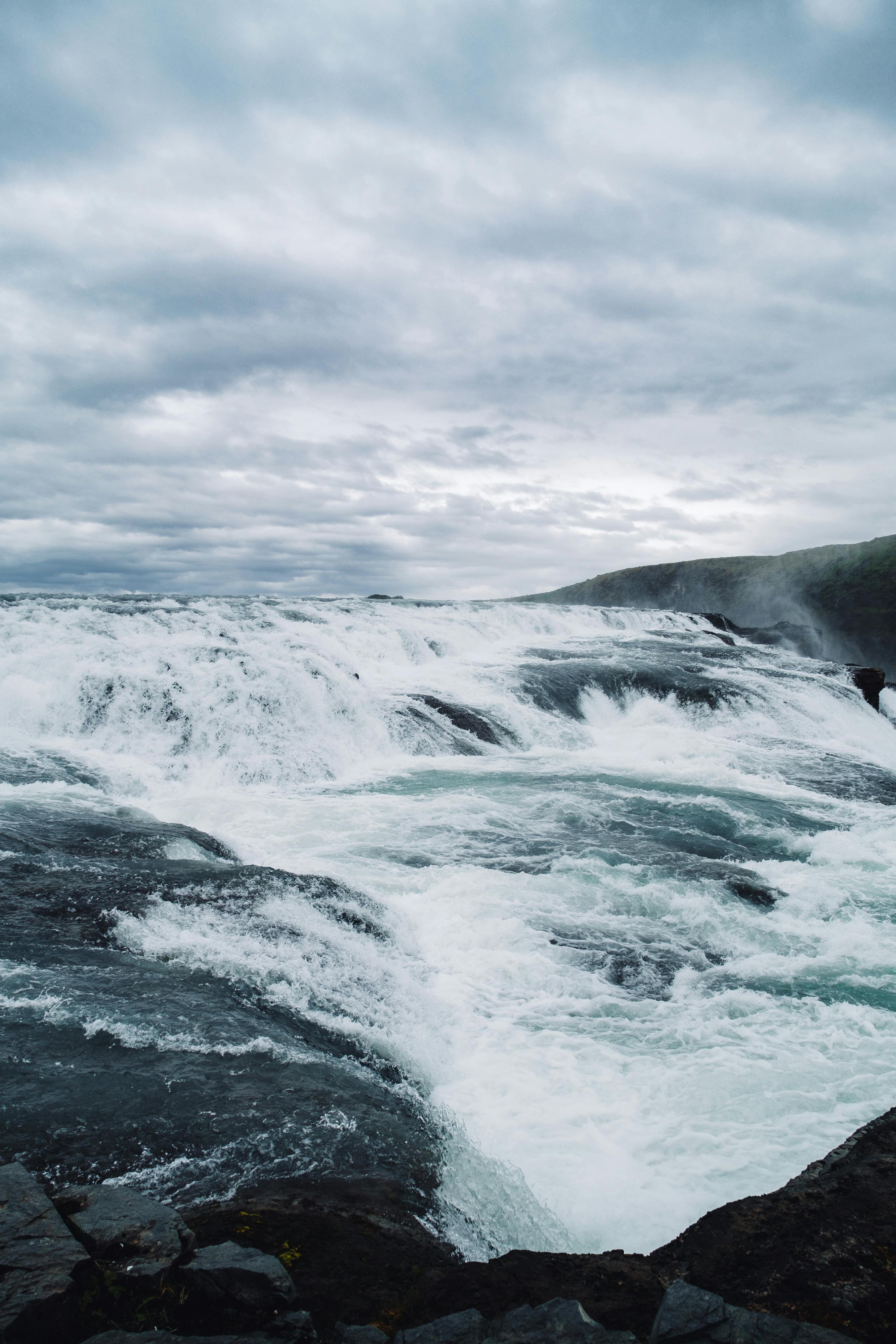 A powerful waterfall cascading under a dramatic, overcast sky, creating a stunning natural spectacle.