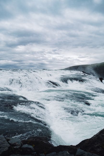 A powerful waterfall cascading under a dramatic, overcast sky, creating a stunning natural spectacle.