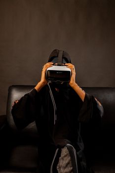 A woman in traditional attire enjoying a virtual reality experience indoors.