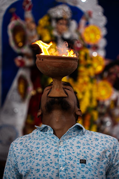Man Holding a Pot with a Flame in His Mouth during a Religious Ritual 