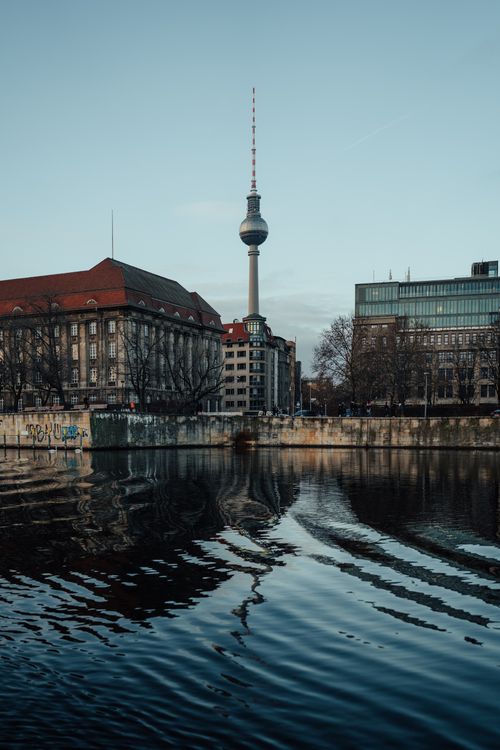Free A tranquil view of the Berlin Fernsehturm with reflection on the river Spree, capturing urban elegance. Stock Photo