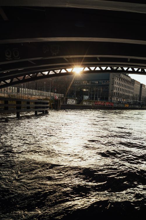 Free Dramatic sunset view under a bridge with cityscape reflecting on a river. Stock Photo