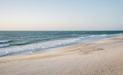 Free Peaceful beach scene with waves gently lapping the shore under a clear sky. Stock Photo