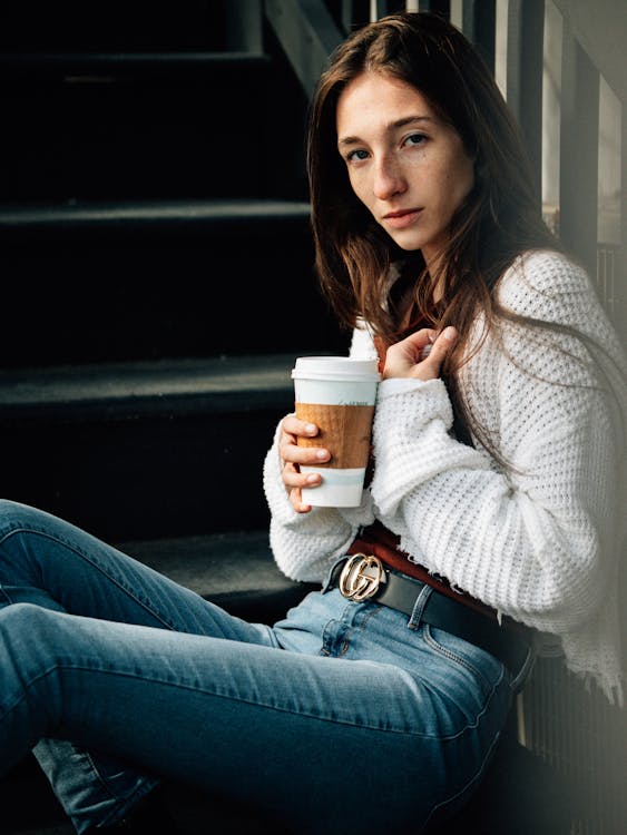 Woman holding a coffee cup sitting on stairs 