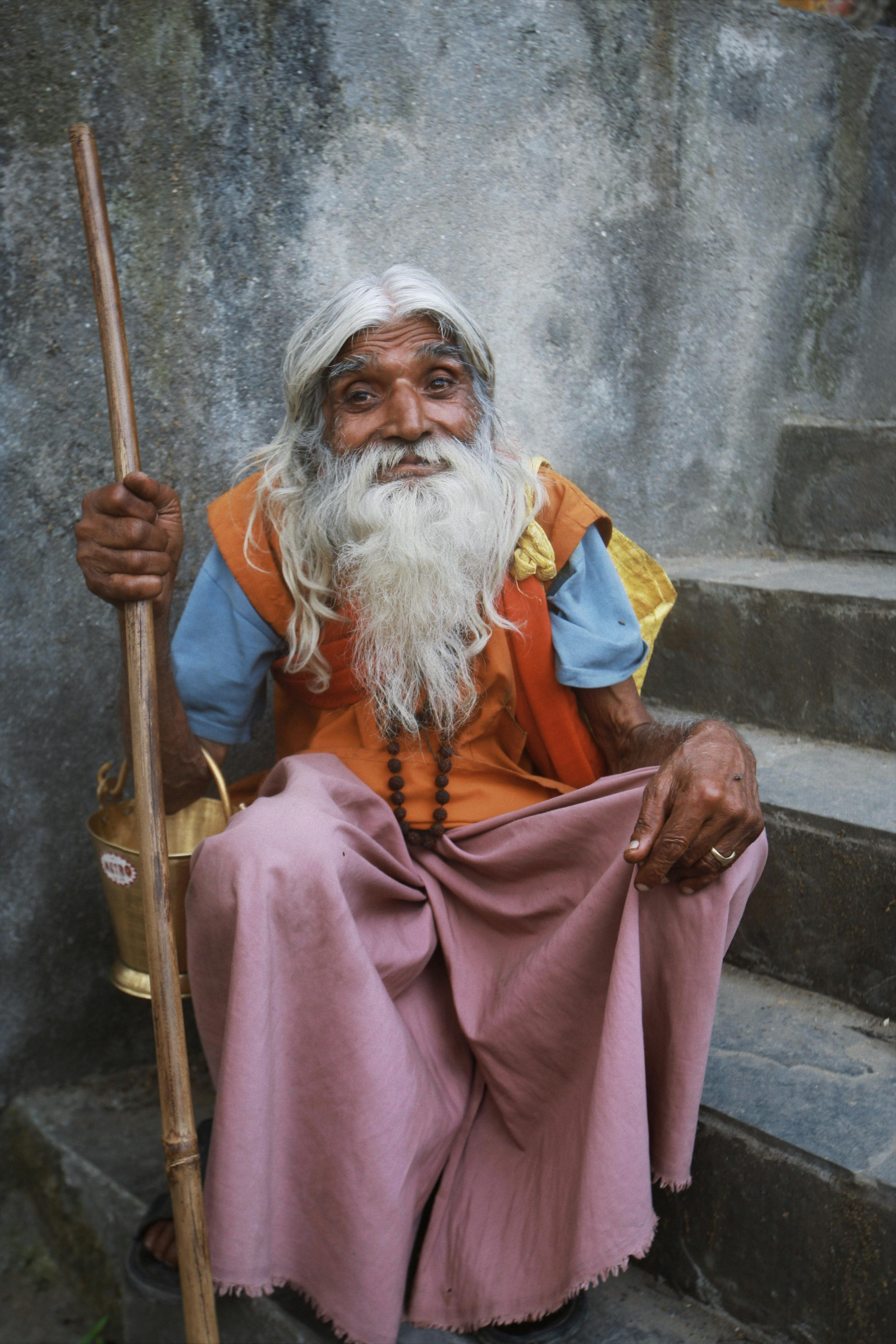 elderly man with a white beard sitting on stairs