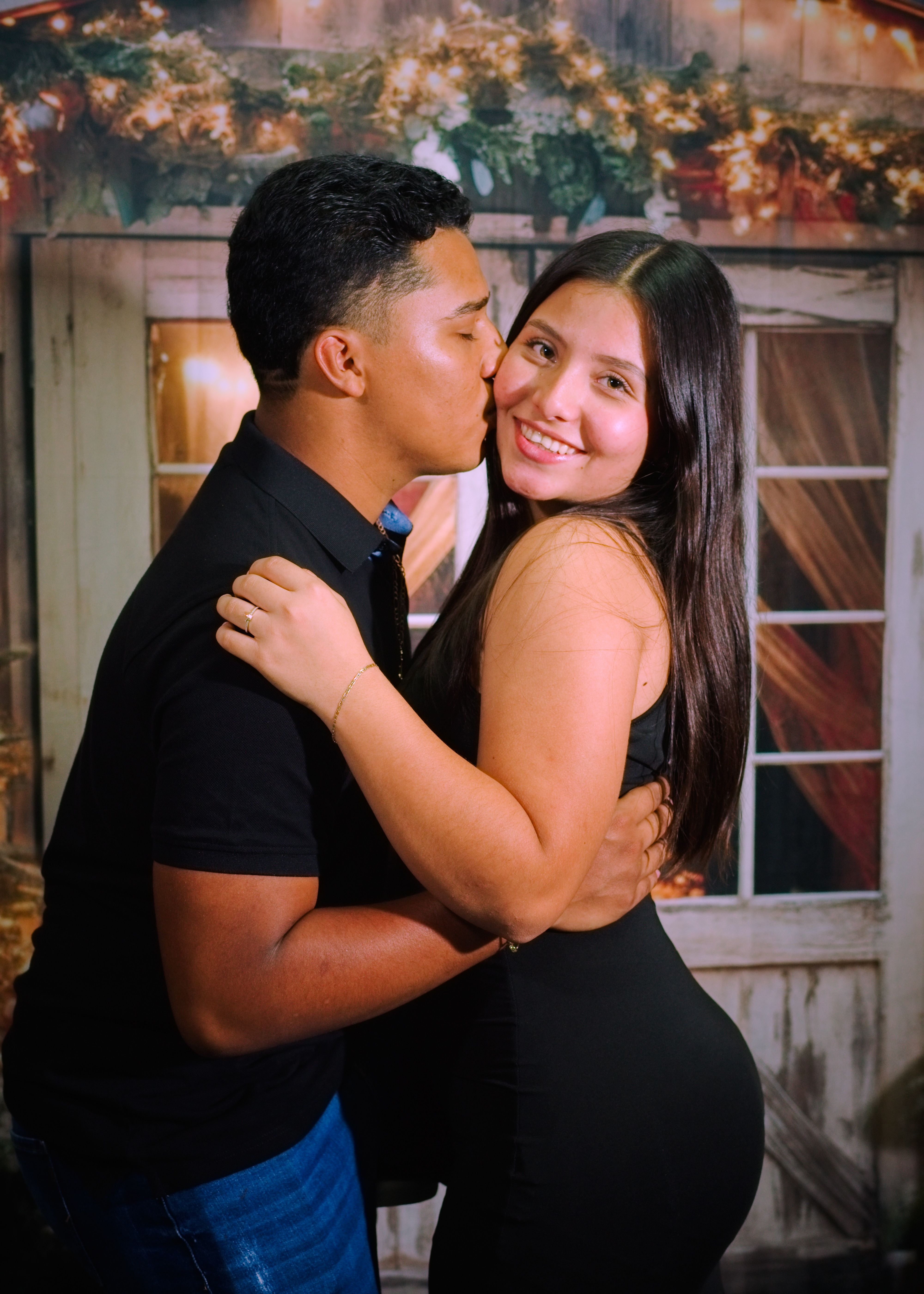 Joyful couple embracing and smiling in a festive setting indoors.