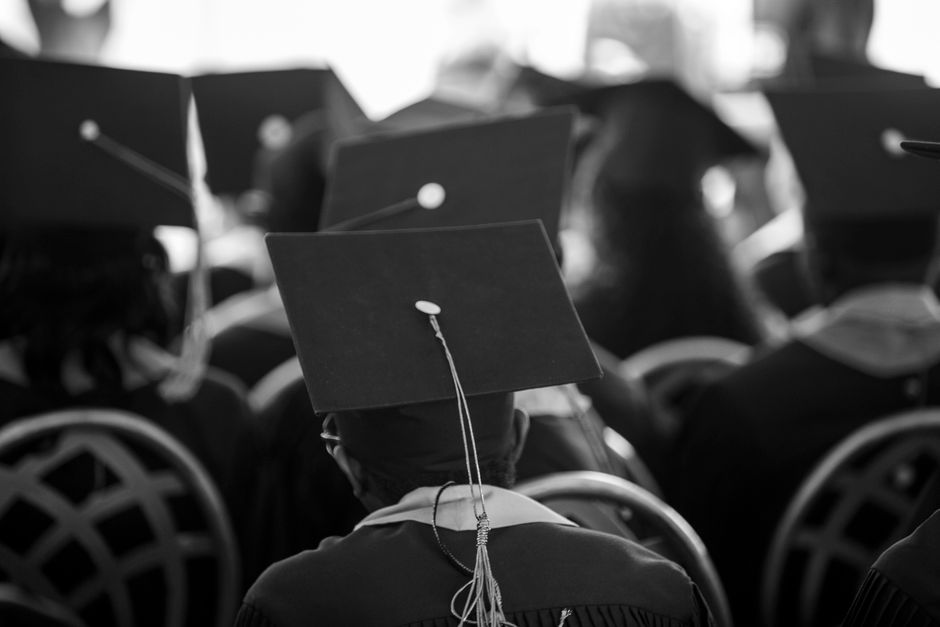 Black and white photograph of students wearing mortarboards at a graduation ceremony.