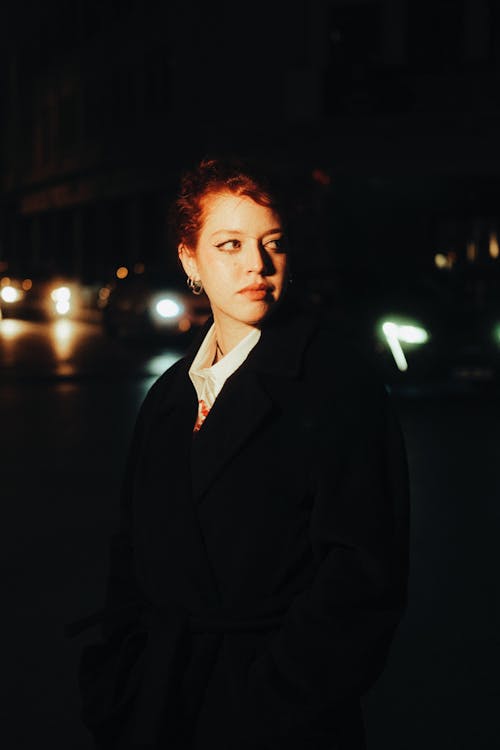 Young Woman in a Coat Standing Outside in the Dark 