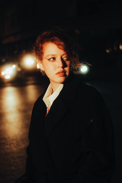 Young Woman Standing Outside in the Dark and Looking Away 