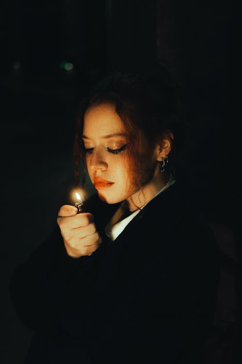 Woman Holding a Lighter in the Dark 