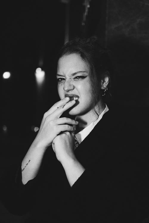 Black and White Photo of a Young Woman Standing Outside and Smoking a Cigarette 