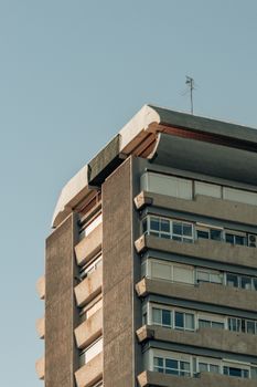 Close-up view of a concrete apartment building with balconies under a clear sky.