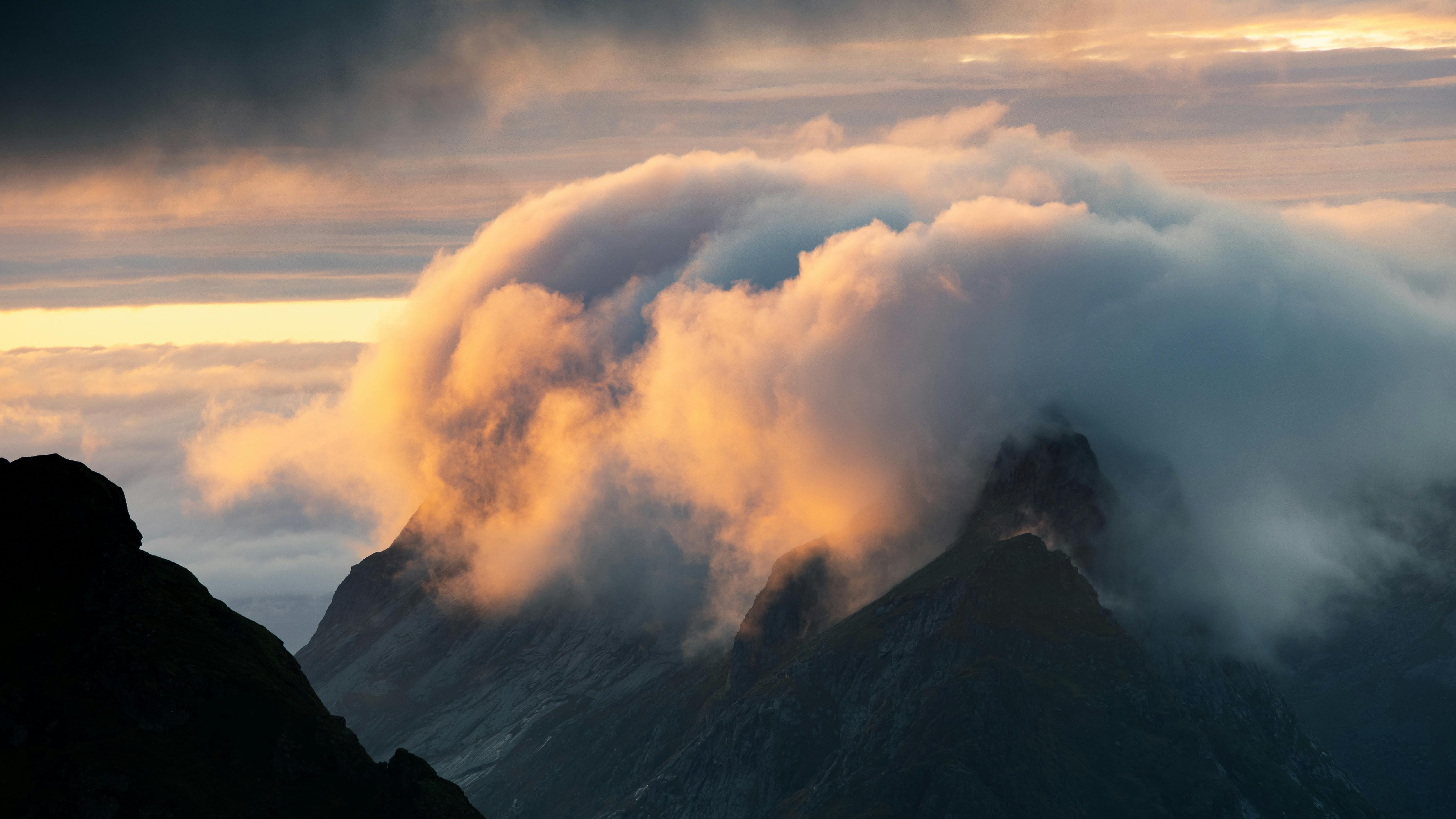 Majestic view of mountains enveloped in clouds during sunset, creating a magical and dramatic scene.