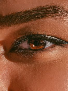 Detailed close-up of a woman's eye with brown iris and black eyeliner.