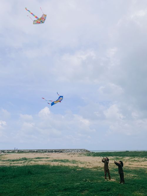 Free Two children enjoy flying colorful kites in a wide open meadow under a cloudy sky. Stock Photo