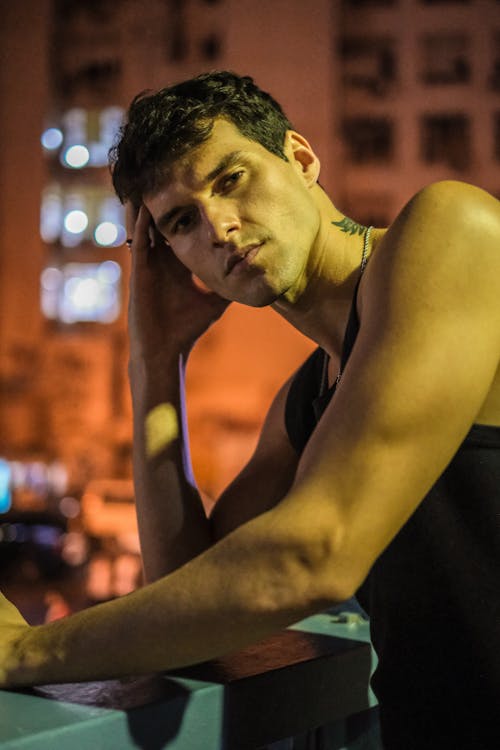 Photo of a Young Man in a Tank Top Posing Outside 