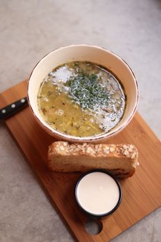 Warm soup with bread and cream served on a wooden tray, perfect for cozy dining.