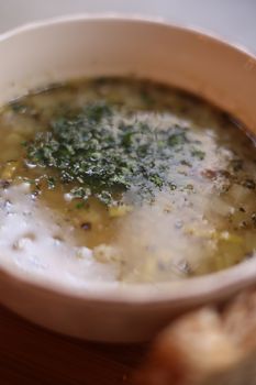 Delicious creamy soup garnished with herbs served in a ceramic bowl.
