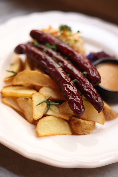 Free Tasty grilled sausages served with crispy potato wedges and dipping sauce. Stock Photo