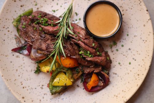 Free Savor grilled beef with vibrant roasted veggies and rosemary sauce, perfect for a gourmet dinner. Stock Photo