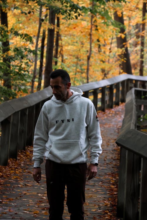 Man in Hoodie Walking in Forest in Autumn