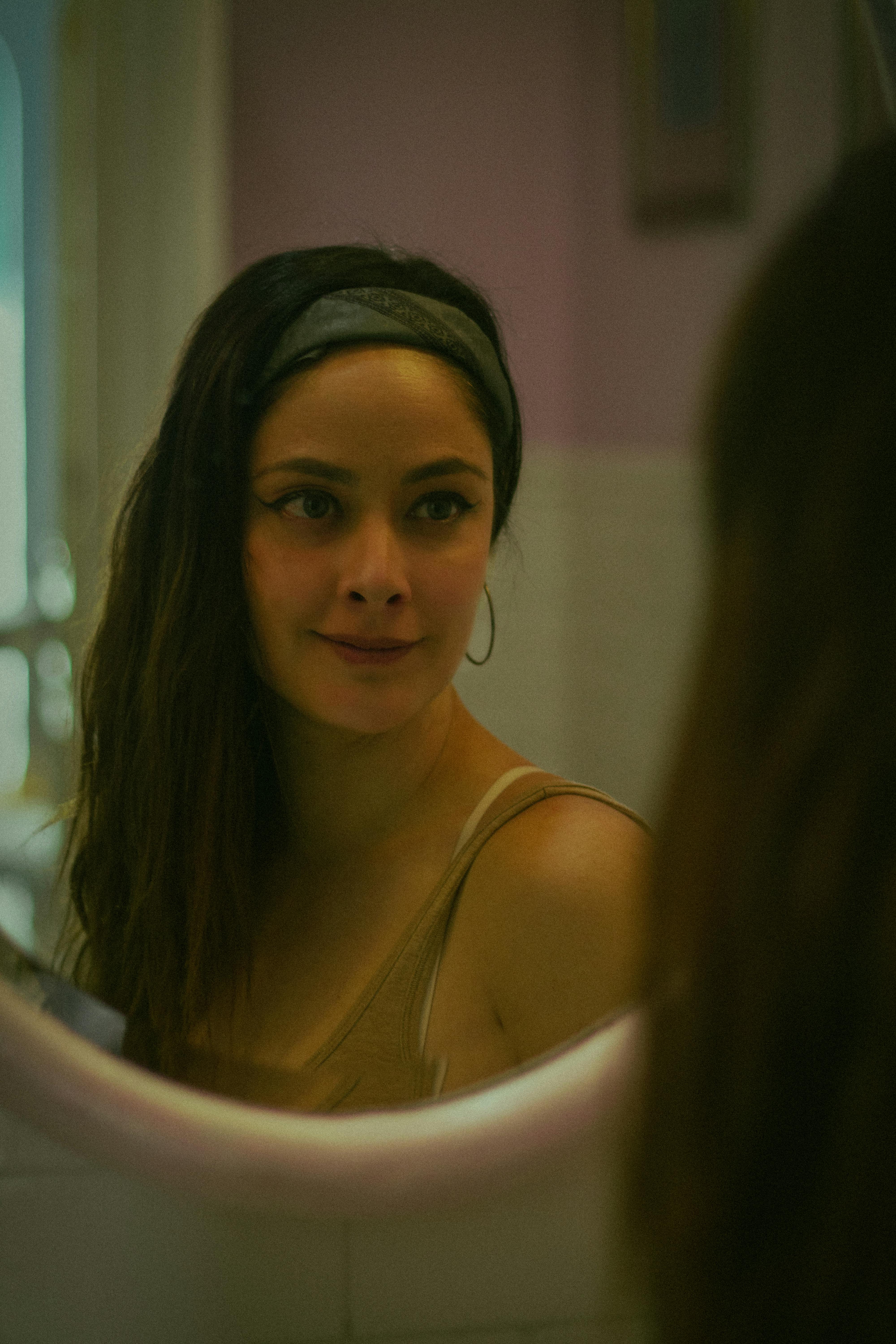 Young Woman Looking at Herself in a Mirror in the Bathroom · Free Stock